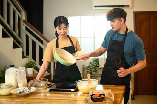 Happy couple preparing to cook pancakes together in a cozy kitchen.