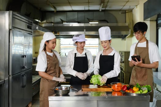 Cooking school instructor explaining food preparation techniques to students in a kitchen.