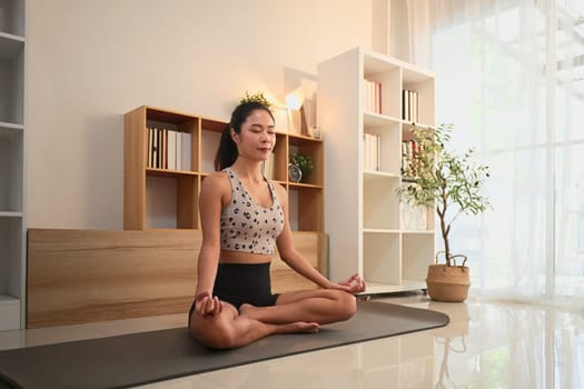 Young woman practicing yoga and mindfulness meditation in a serene home.