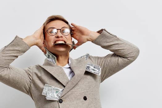 excited man with glasses wearing beige jacket holding cash currency notes and celebrating success with joyful emotion on white studio background digital nomad lifestyle concept
