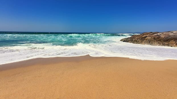 A breathtaking beach scene that highlights golden sand alongside rolling waves beneath a serene, clear blue sky