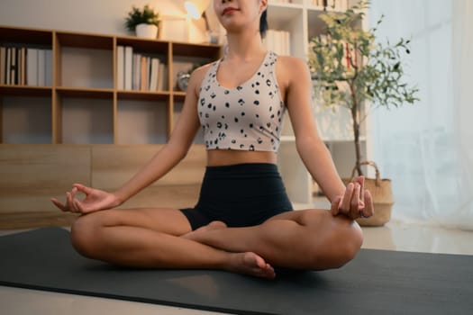Focused female practicing mindfulness and breathing exercises during home yoga session.
