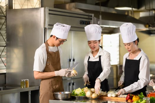 Group of cooking school students preparing fresh vegetables during a culinary class.