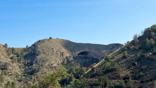 The breathtaking mountain view showcases hills and vibrant foliage beneath an expansive bright blue sky