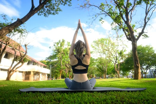 Young woman practicing yoga in a peaceful green park. Mindfulness concept..