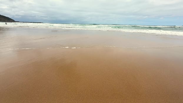 Imagine a tranquil beach scene showcasing soft golden sand and gentle ocean waves rolling in beneath a cloudy sky