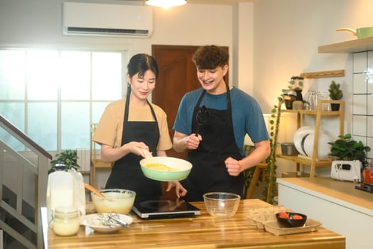 Happy couple preparing to cook pancakes together in a cozy kitchen.