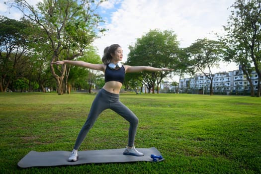 Young woman practicing yoga in a peaceful green park. Mindfulness concept..