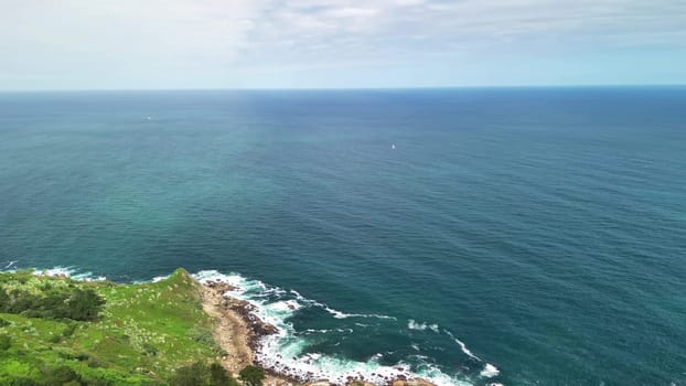 Experience breathtaking aerial views of cliffs and vibrant greenery along the picturesque coastal shoreline