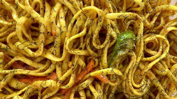 A colorful plate of stirfried noodles seasoned with aromatic herbs and fresh, flavorful seasonal vegetables