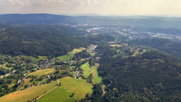 An aerial view beautifully captures a vibrant green landscape with a serene town nestled gently within nature