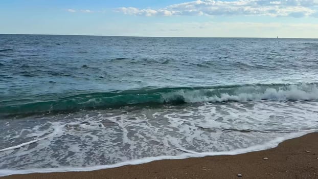 This is a serene beach scene beautifully showcasing gentle waves combined with a clear, radiant blue sky