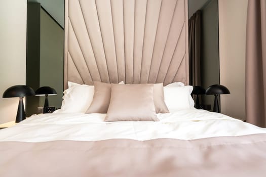 A cozy modern hotel bed with soft pillows, elegant headboard and stylish interior design.