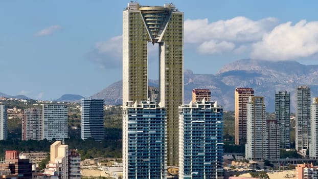 A breathtaking view of a magnificent skyscraper towering among urban buildings under a clear blue sky