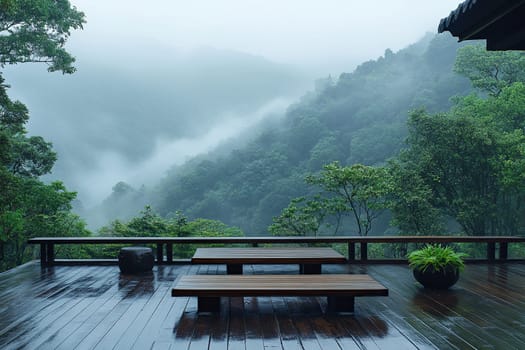 Misty mountains stretch across the horizon viewed from a wooden deck. Their lush green trees are partially obscured by fog, creating a tranquil and serene atmosphere.