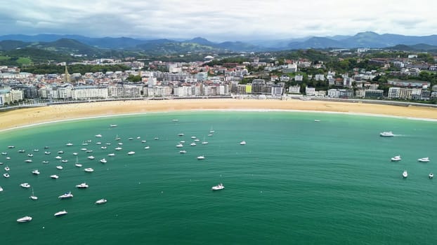 A stunning aerial shot beautifully showcasing a tranquil beach, boats gently bobbing, and a picturesque cityscape