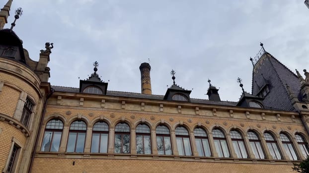 A grand historic buildings intricate design and large windows are beautifully showcased under a cloudy sky