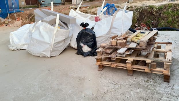 An extensive view of a construction area that prominently showcases numerous waste bags and stacked wooden pallets