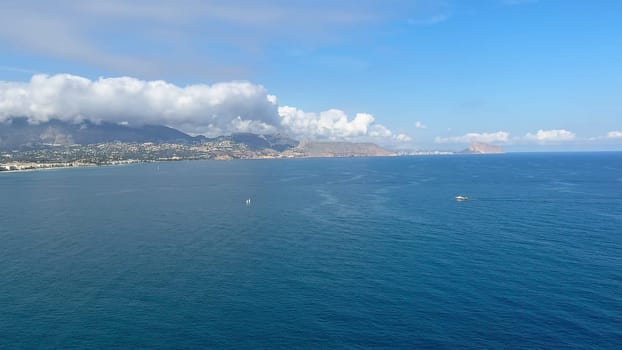 A truly picturesque coastal view showcasing calm azure waters, serene skies, and distant majestic mountains