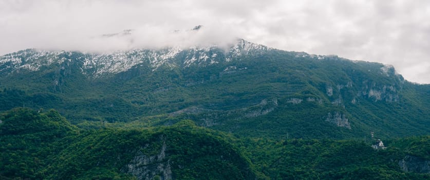 Green mountains partially covered in mist and snow, offering a tranquil and scenic view of nature's beauty