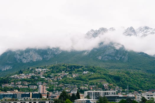 Lecco, Italy - 19.05.2024: Majestic mountain view with misty peaks and bustling cityscape.