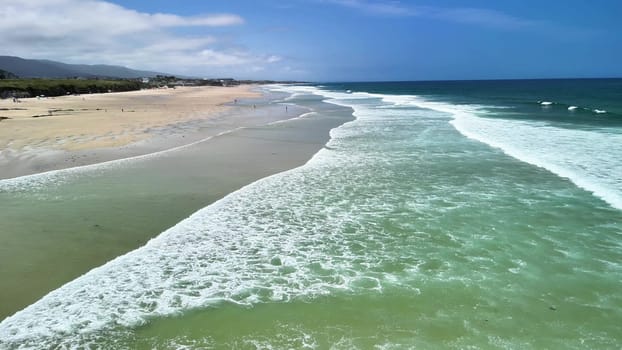 Immerse yourself in the stunning beauty of rolling ocean waves gracefully crashing against a peaceful, sandy beach