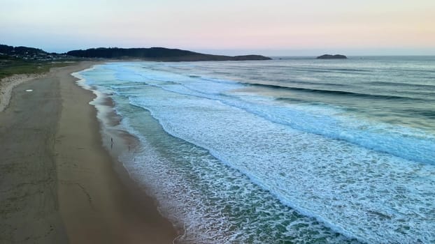 Experience the tranquil beauty of waves lapping against a serene beach at dusk, perfect for relaxation
