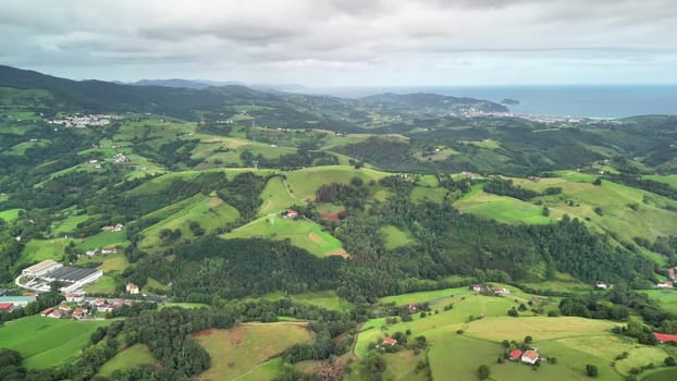 Stunning and breathtaking aerial imagery of rolling green hills beautifully meeting the coast beneath a cloudy sky