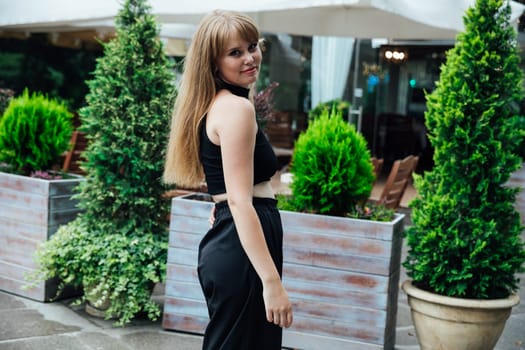 Beautiful female student in black street clothes walking around the city