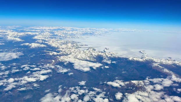An absolutely breathtaking aerial shot captures stunning snowcovered peaks with a clear and vibrant blue sky above