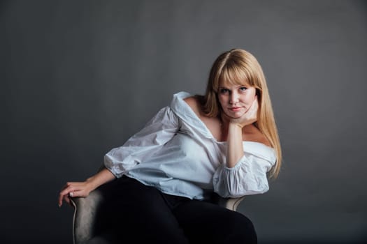 Portrait of a beautiful blonde young woman on a gray fashion background