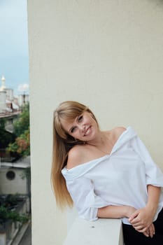 Young woman standing on the balcony on the street and smiling