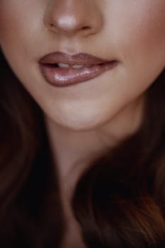 Close-Up of Woman with Glossy Lips and Radiant Skin - Natural Beauty and Minimalistic Makeup Concept, with long dark hair styled in waves. the girl bit her fur coat. High quality photo