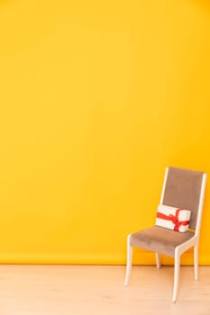 One gray chair with a holiday gift in the interior of a yellow room