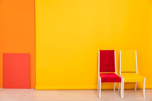 Two old chairs red and yellow in the interior of an orange room