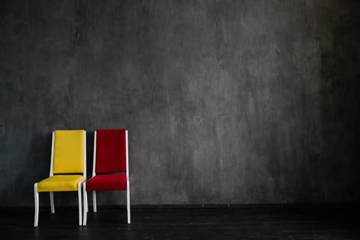 Two old chairs red and yellow in the interior of a gray room