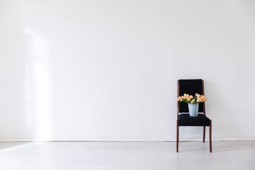 One black chair with flowers in the interior of a white room with a window