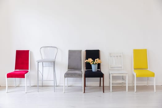 Six different chairs with a basket of flowers in the interior of a white room