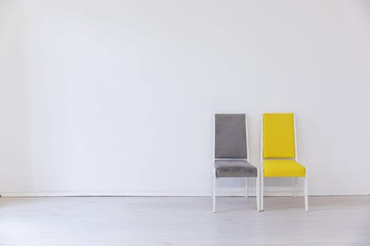 Two old chairs gray and yellow in the interior of a white room