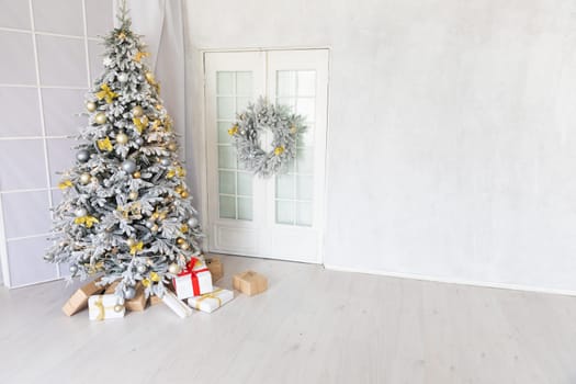 Snow-covered Christmas tree with gifts decorated for the new year in the interior