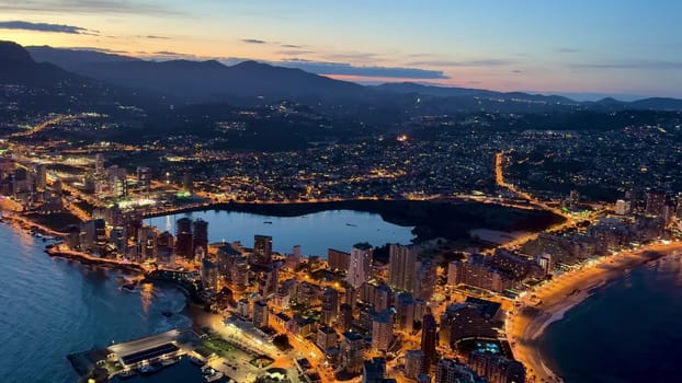 Aerial view of a vibrant cityscape and stunning coastline at dusk, beautifully lighting up the landscape