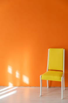 One old yellow chair against an orange wall