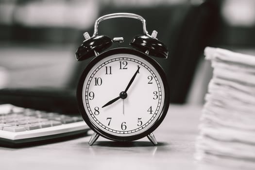 alarm time clock on office working table for working hours black and white
