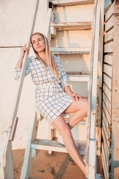 Beautiful blonde woman smiling in summer dress on the beach by the sea