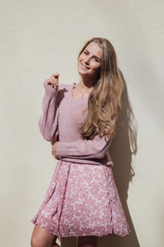 Blonde woman in summer pink dress on street smiling