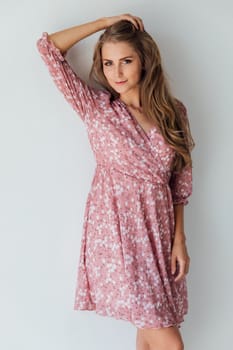 Beautiful fashionable blonde woman in summer pink dress on white background
