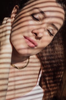 Woman brunette portrait and light shadow from blinds window