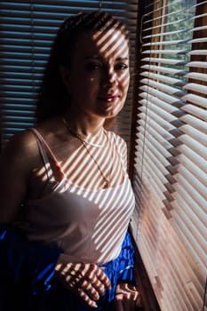 Woman brunette portrait and light shadow from blinds window
