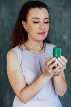 Brunette woman in summer dress blowing out a green candle