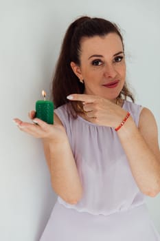 Brunette woman in summer dress blowing out a green candle